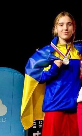 Марія Маковоз на п’єдесталі з медаллю та прапором України
